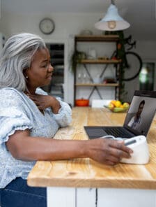 Senior woman talking to her doctor on her computer at home