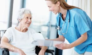 Woman doctor helping senior woman in wheelchair