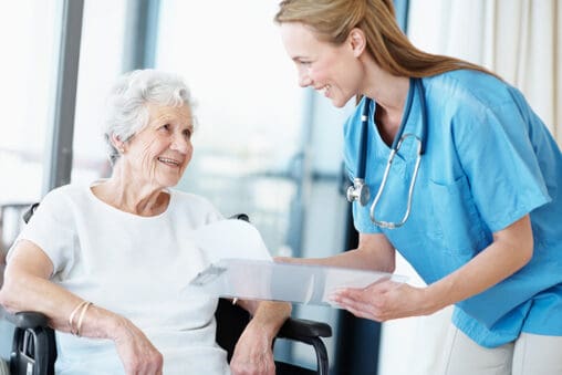 Woman doctor helping senior woman in wheelchair
